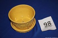 Top-down view of the yellow glazed flower pot with interior and drainage holes visible. Shows overall shape and glaze condition.