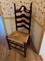 Front view of the wooden ladder back chair showing the woven seat and the turned wooden frame with three horizontal slats on the backrest.