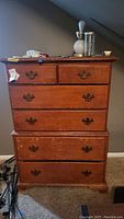 Front view of six-drawer wooden dresser with visible scratches and scuffs. Two smaller top drawers and four larger bottom drawers with metal pull handles.