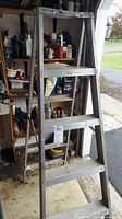 Front view of the aluminum step ladder showing 3 steps and visible rust, stains, and dents.