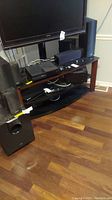 Photo showing TV stand with Onkyo receiver and multiple speakers including subwoofer placed around it.