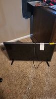 Front view of 32 inch LG TV with power cord resting on beige carpet.