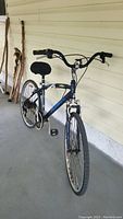 Front angled view of the blue Magna Oasis bike showing frame, handlebars, pedals, and flat tires.