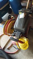 Top and side view of Durabuilt air compressor with attached yellow hose and orange hose reel on the side, black handle visible