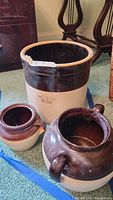 Front view of three stoneware crocks including a large 3-gallon crock and two smaller pots, showing their body, color, and marking