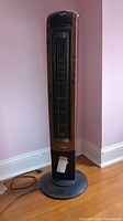Front view of the Lasko Wind Curve tower heater showing its faux wood curved panel sides and black front grille.
