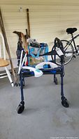 Blue rollator walker next to walking canes and a tote bag on porch