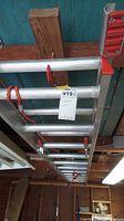 Aluminum extension ladder showing rungs and adjustment mechanism with red rope, hanging in garage.