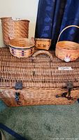 Image showing large rectangular wicker chest and four smaller baskets on top including handled Longaberger baskets and waste can