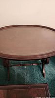 Top view of oval wooden tabletop with scratches, showing removable glass overlay.