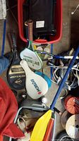Photo showing paddle racquets, tennis racquets, and balls in a storage area with assorted sports equipment.