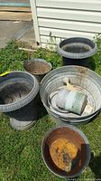 Set of five garden containers including plastic pedestal planters and metal tubs, showing overall weathering and rust.