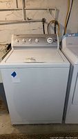 Front view of Kenmore washer in basement setting, showing control panel and overall unit.