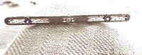 Front view of antique bar pin showing filigree design, diamond center stone, and two sapphire stones.