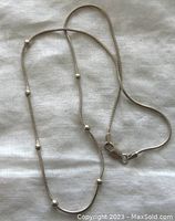 Full view of the sterling silver necklace laid flat showing the beaded chain with lobster clasp.