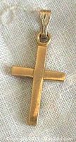 Front view of a small yellow gold cross pendant with polished finish, showing its face and bail for chain attachment.