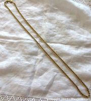 Full view of the 20 inch 10K yellow gold rope chain necklace laid out on a white cloth background showing overall length and chain design.