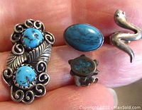 Close-up photo showing all four single sterling silver earrings held in hand. Three have turquoise stones and one is a snake shape.