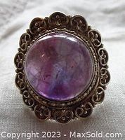 Front view showing large round purple amethyst cabochon and decorative silver frame with heart embellishments.