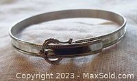 Full view of the sterling silver child's bangle showing the buckle closure and smooth polished finish, with subtle edge detailing.