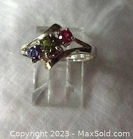 Front and side view of vintage sterling silver ring with three prong-set colored stones: amethyst, peridot, ruby-colored stones. Ring is size 7.