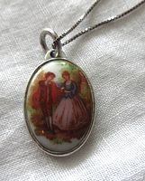 Close-up of oval pendant showing porcelain romantic scene and sterling silver frame