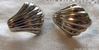Front view of the polished scallop shell formed sterling silver earrings showing ribbed texture and curved design.