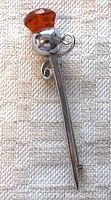 Photo of the vintage kilt pin showing faceted orange glass stone and roll over clasp.