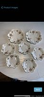 Full view of 7 scalloped floral plates arranged on table, showing 5 small and 2 larger luncheon plates.