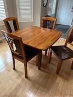 Table with both drop leaves raised and four chairs arranged around