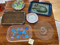 Overview of six trays and plates showing different designs and materials on a wooden table.