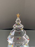Close-up of the Swarovski crystal Christmas tree ornament showing clear faceted crystal layers with red and gold crystal decorations and a gold star on top.
