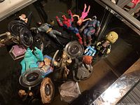 Photo shows assorted Disney Infinity figures and other collectible superhero figures laid out on a black surface. Figures include Spider-Man, Captain America, Batman, and others.