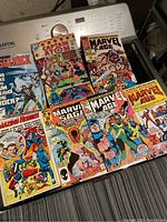 Photo showing seven Marvel comic books in colorful covers with various characters and titles.