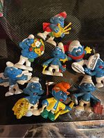 Eight Smurf figurines in various poses with some paint chipping and damage visible