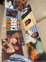 Photo of nine soul vinyl records arranged on a beige couch, showing album covers with portraits of various artists.