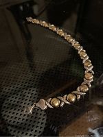 Full view of a sterling silver bracelet with alternating heart shapes and gold-tone balls, laid flat showing the lobster clasp.