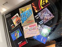 Nine video game manuals spread on a black surface including Super Mario World, Captain Comic, Legend of Zelda Tips & Tactics guide, and Nintendo Power.