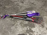 Four mops of different styles laid on a concrete floor showing handles and mop heads