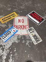 Five business and traffic metal signs arranged on a concrete surface showing wear. Signs include No Parking, Authorized Personnel Only, Private Property, Closed sign, and a Georgia license plate.