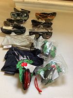 Seven pairs of sunglasses arranged in two rows with accessories in front on a white surface.