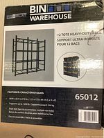 Box label showing brand name Bin Warehouse with image of the assembled 12 tote heavy-duty rack. Dimensions and features listed: 68 W x 68 H x 27 D inches, supports 1200 lb, dual slide bars for multiple tote sizes, easy to assemble.