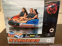 Front of original box showing three riders on the Striker3 tube in use, branding and color scheme visible