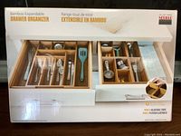 Box front showing bamboo expandable drawer organizer with divided compartments for cutlery and kitchen utensils.