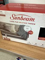 Front of box showing Sunbeam Luxe Fur Heated Throw blanket showing ultra silky luxe fur fabric and push button control.