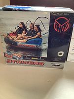 Box front showing three people riding the Striker 3 tube on water and product name/logo