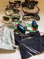 Overall view of the sunglasses lot including several pairs of sunglasses with price tags and protective pouches.