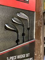 Photo of three Kirkland wedges in original foam packaging showing club heads and shafts.