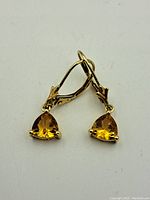 Front view of the pair of triangular cut topaz earrings set in 10K gold with lever-back clasps.
