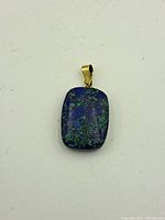 Front view of a rectangular lapis pendant with 14k gold bail, showing mottled blue and green stone surface.
